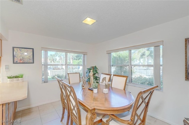 dining space featuring light tile patterned floors, a textured ceiling, and a wealth of natural light