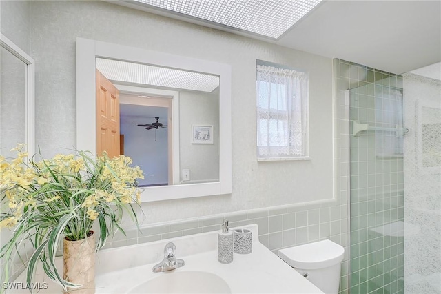 bathroom featuring walk in shower, toilet, sink, and tile walls