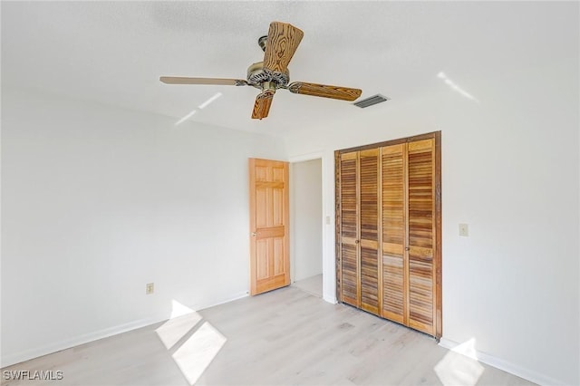 unfurnished bedroom with light hardwood / wood-style flooring, a closet, and ceiling fan