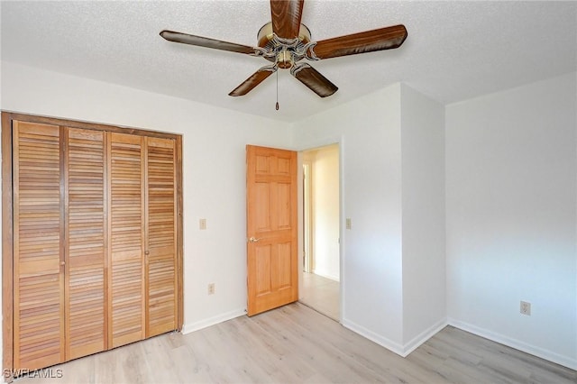 unfurnished bedroom featuring ceiling fan, a textured ceiling, a closet, and light wood-type flooring