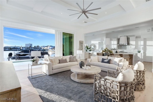 living room featuring coffered ceiling, wood-type flooring, and a water view