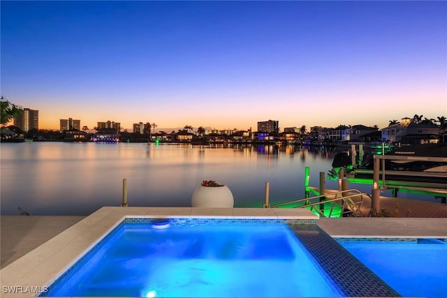 pool at dusk featuring a water view