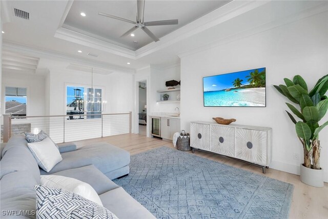 living room with a raised ceiling, ornamental molding, hardwood / wood-style flooring, and sink