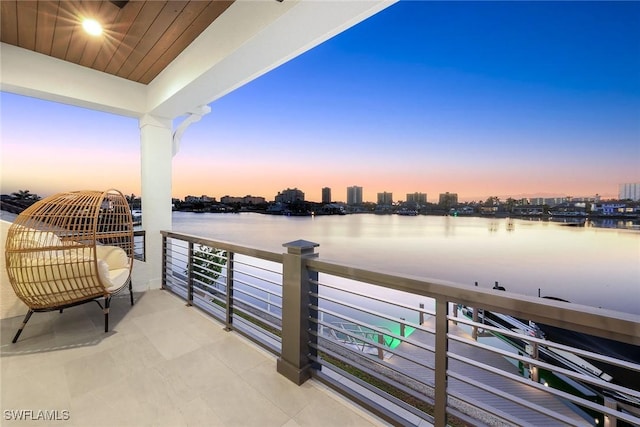 balcony at dusk featuring a water view