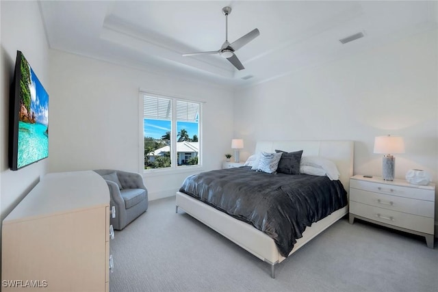 bedroom featuring ceiling fan, a tray ceiling, and light carpet