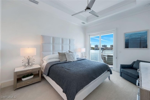 bedroom featuring access to outside, ceiling fan, a tray ceiling, a water view, and light carpet