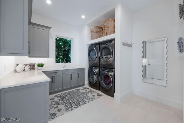 washroom featuring cabinets, stacked washing maching and dryer, sink, and washing machine and clothes dryer