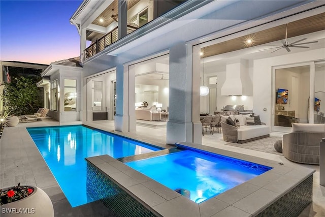 pool at dusk featuring area for grilling, a patio area, ceiling fan, and an in ground hot tub