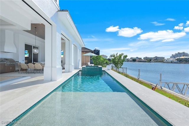 view of pool with a water view, grilling area, exterior kitchen, and a patio area