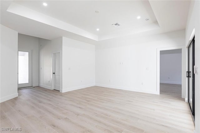 unfurnished room with a raised ceiling and light hardwood / wood-style flooring