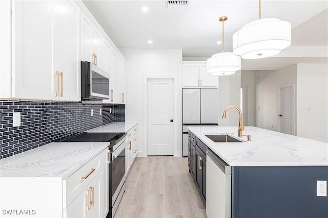 kitchen with pendant lighting, sink, stainless steel appliances, an island with sink, and white cabinets