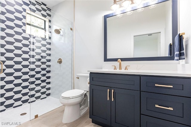 bathroom featuring vanity, toilet, and a tile shower