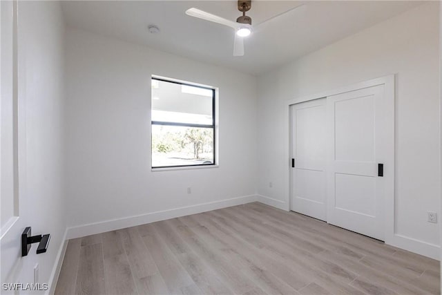 unfurnished bedroom with ceiling fan, light wood-type flooring, and a closet