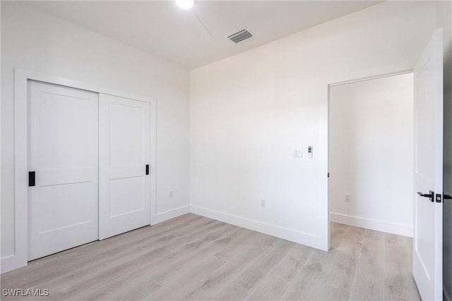 unfurnished bedroom featuring light hardwood / wood-style floors and a closet