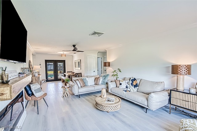 living room featuring french doors, crown molding, and light hardwood / wood-style floors