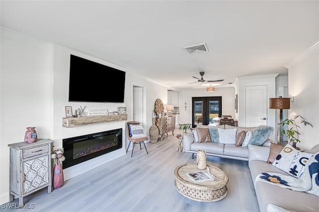 living room featuring crown molding, french doors, ceiling fan, and light wood-type flooring