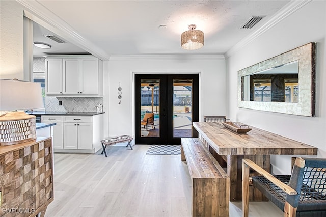 dining room with crown molding, light wood-type flooring, and french doors