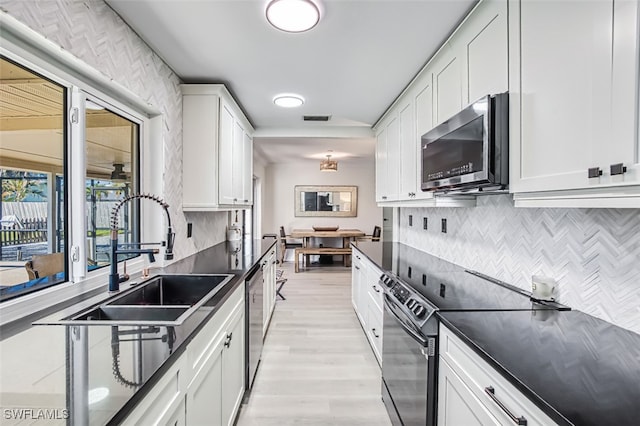 kitchen with sink, appliances with stainless steel finishes, light hardwood / wood-style floors, decorative backsplash, and white cabinets