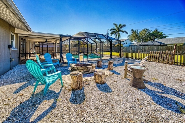 view of patio with a fenced in pool, glass enclosure, and a fire pit