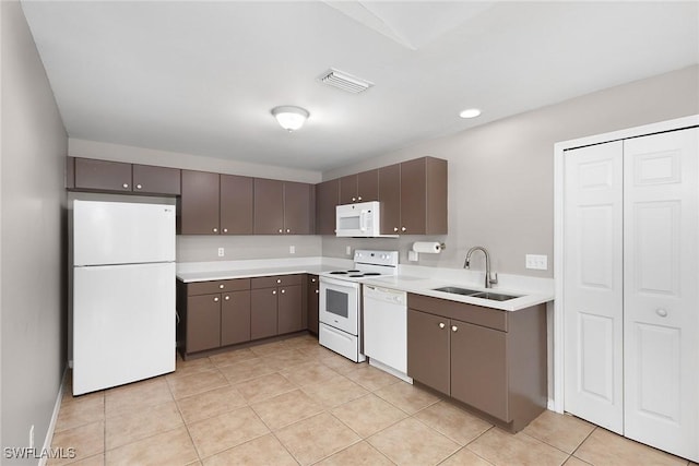 kitchen featuring dark brown cabinetry, light tile patterned flooring, sink, and white appliances