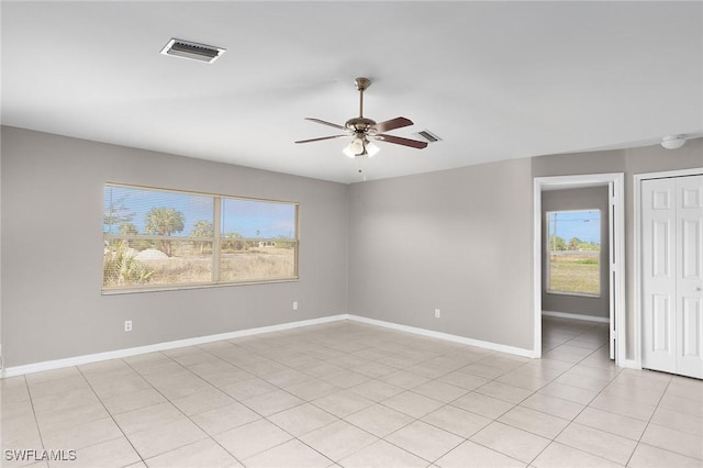 tiled spare room featuring ceiling fan and plenty of natural light