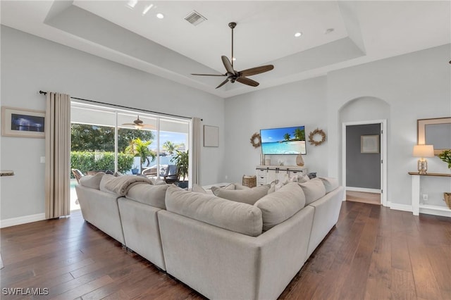 living room featuring ceiling fan, dark hardwood / wood-style flooring, and a tray ceiling