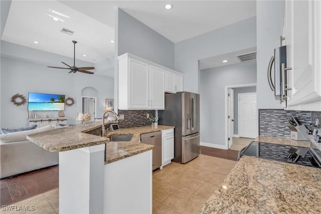 kitchen with stainless steel appliances, stone countertops, white cabinets, and kitchen peninsula