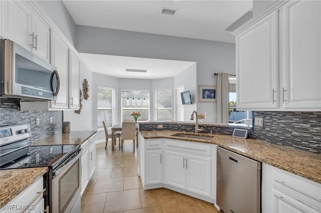 kitchen featuring stainless steel appliances, white cabinetry, sink, and dark stone counters