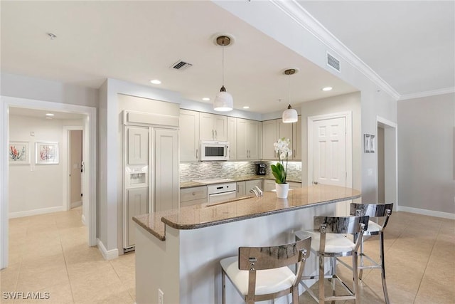 kitchen with pendant lighting, dark stone countertops, decorative backsplash, ornamental molding, and paneled built in fridge