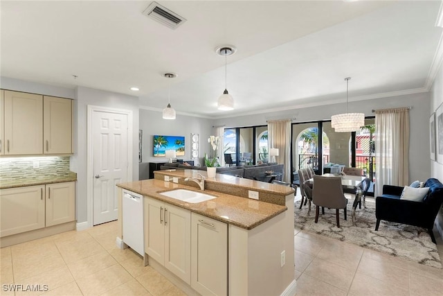 kitchen with sink, white dishwasher, light stone counters, an island with sink, and decorative light fixtures