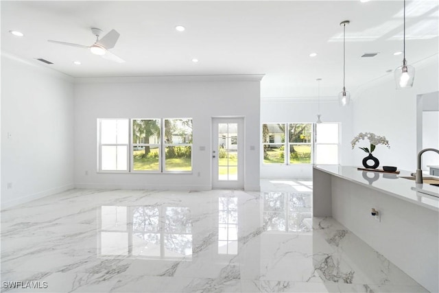 unfurnished living room with ornamental molding, a healthy amount of sunlight, and ceiling fan