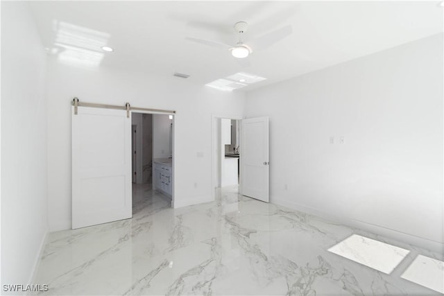 unfurnished bedroom with a barn door, ceiling fan, and ensuite bath