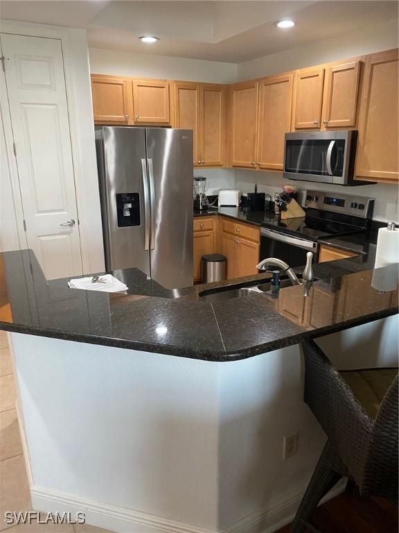 kitchen featuring light brown cabinetry, recessed lighting, appliances with stainless steel finishes, and a sink