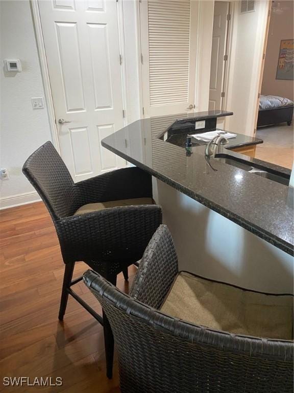 kitchen featuring visible vents, wood finished floors, baseboards, and a sink