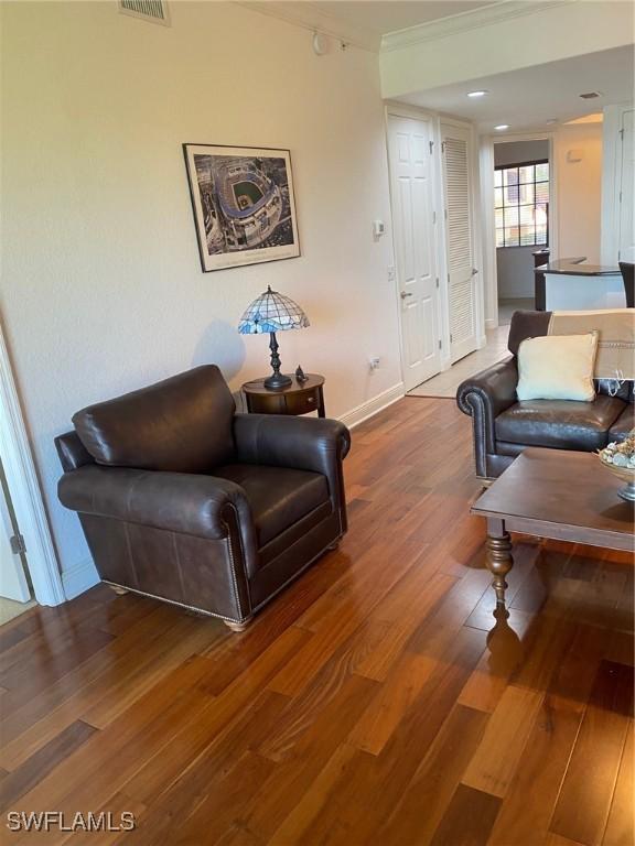 living room with wood-type flooring and ornamental molding