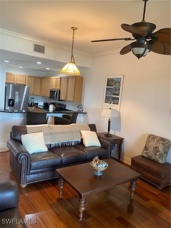 living room with crown molding, dark hardwood / wood-style floors, and ceiling fan