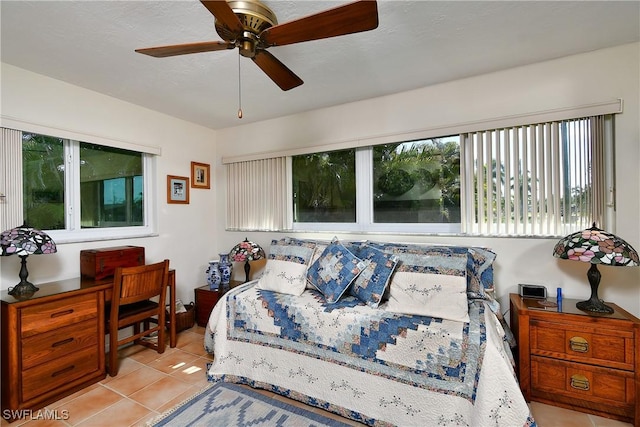 bedroom with light tile patterned floors, ceiling fan, and a textured ceiling