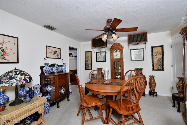 carpeted dining room with a textured ceiling, baseboards, visible vents, and a ceiling fan