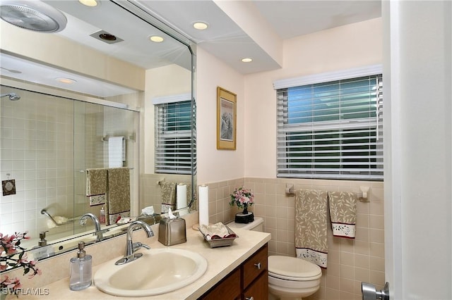 full bath featuring tile walls, recessed lighting, toilet, a shower with shower door, and vanity