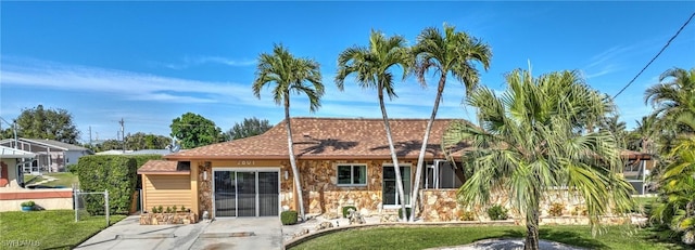 view of front of home featuring stone siding, a patio, and a front lawn