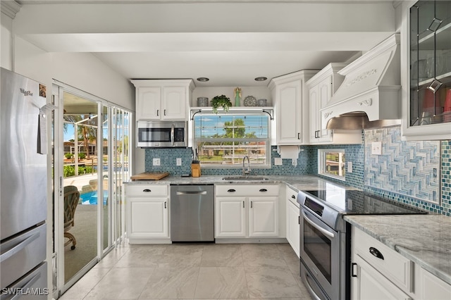 kitchen with sink, white cabinets, stainless steel appliances, and premium range hood