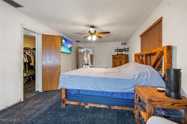 bedroom with dark carpet, a walk in closet, a closet, and ceiling fan