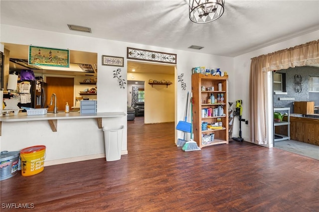 interior space featuring a breakfast bar, sink, black refrigerator with ice dispenser, dark hardwood / wood-style floors, and kitchen peninsula