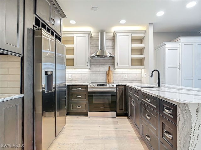 kitchen featuring sink, white cabinets, wall chimney exhaust hood, stainless steel appliances, and light hardwood / wood-style flooring