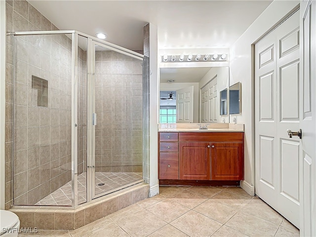 bathroom with walk in shower, tile patterned floors, toilet, vanity, and ceiling fan