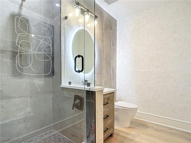 bathroom featuring vanity, wood-type flooring, a shower with shower door, and toilet