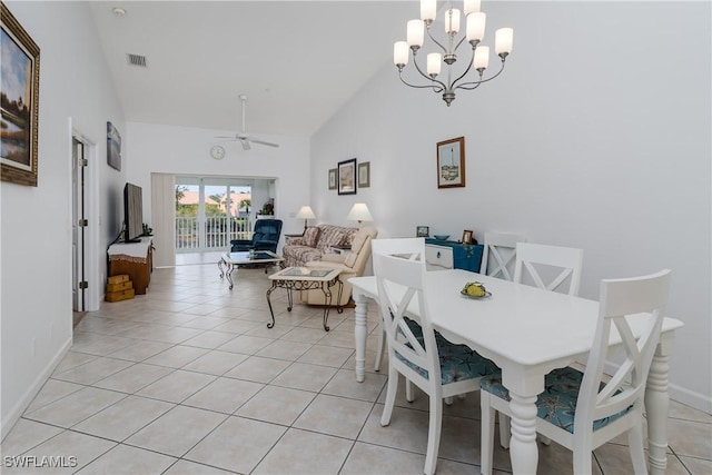 tiled dining room with ceiling fan with notable chandelier and high vaulted ceiling