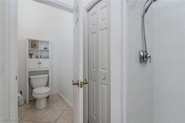 bathroom featuring tile patterned flooring, toilet, and tiled shower