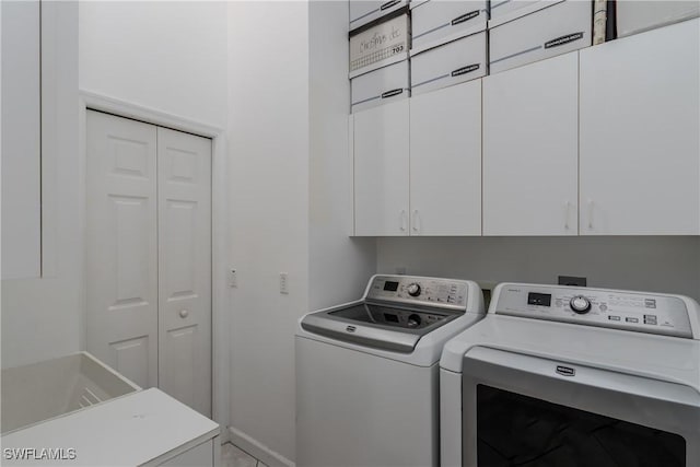 clothes washing area featuring washer and clothes dryer and cabinets