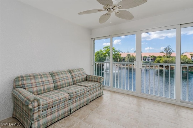 living room with a water view, ceiling fan, and light tile patterned floors